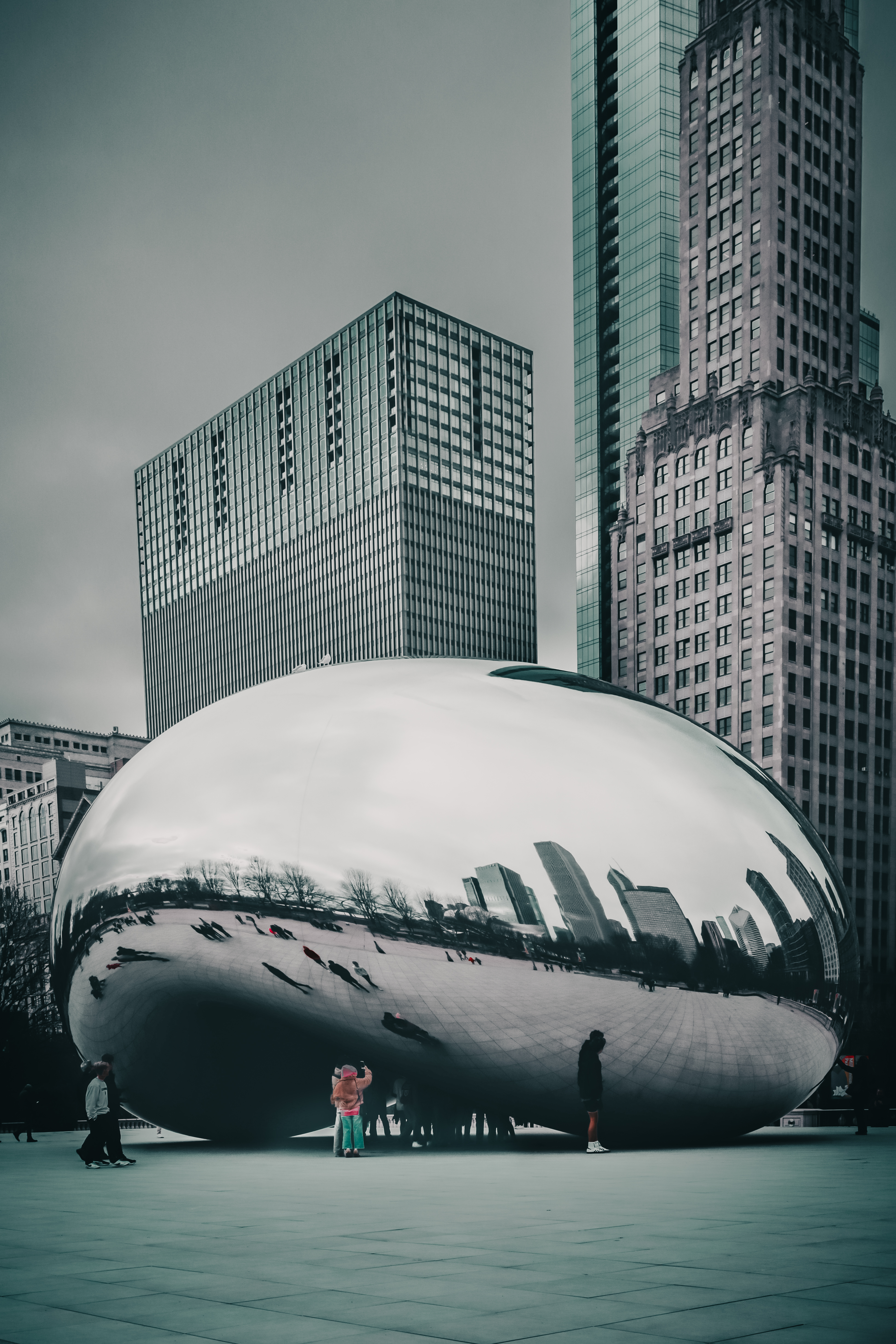 Cloud Gate 'The Bean' in cold tones — skyscrapers reflected across the mirrored surface, pedestrians below