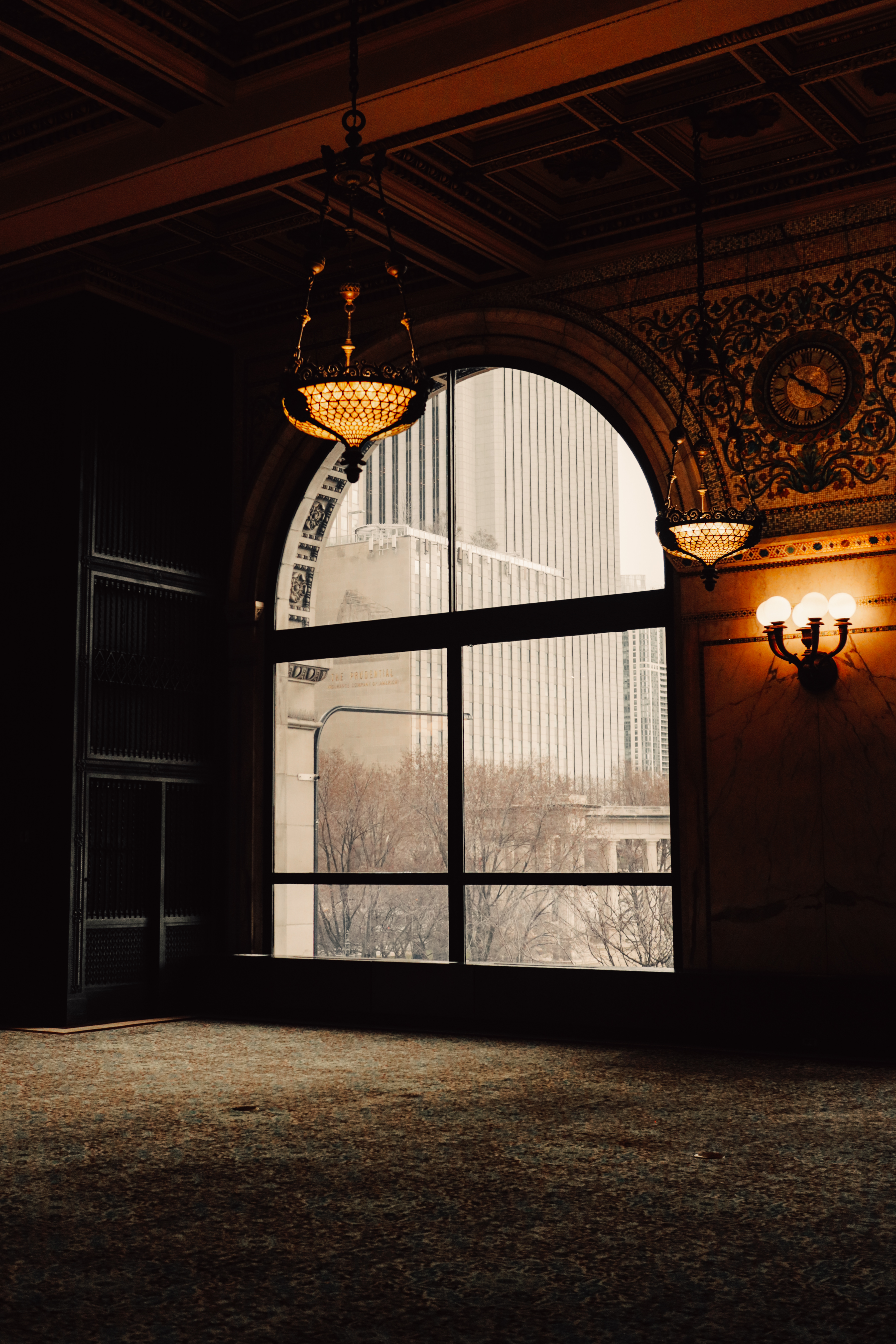 Dark ornate reading room at the Chicago Cultural Center — arched window frames the city