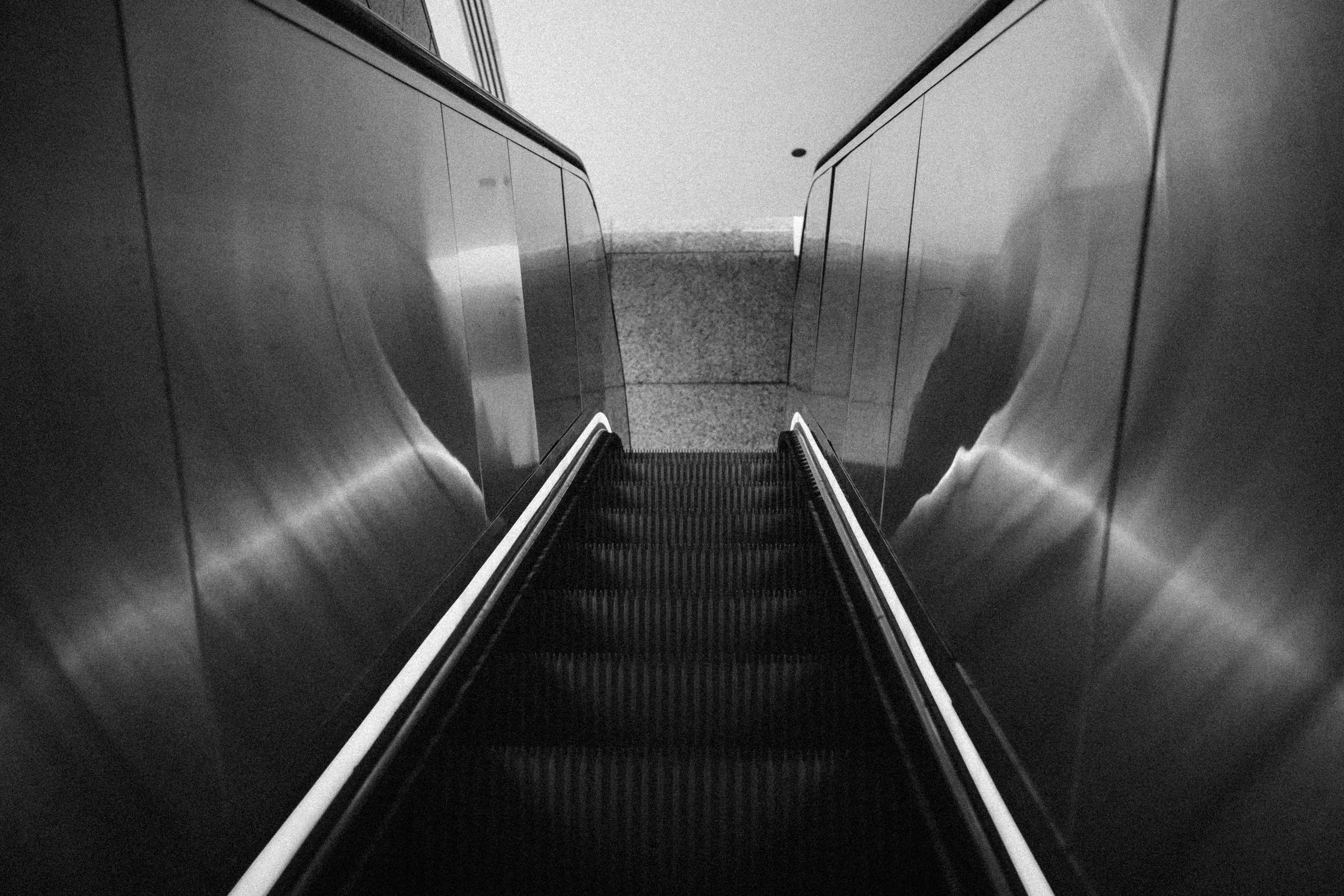 CTA escalator in black and white — looking up from the bottom, steel panels either side