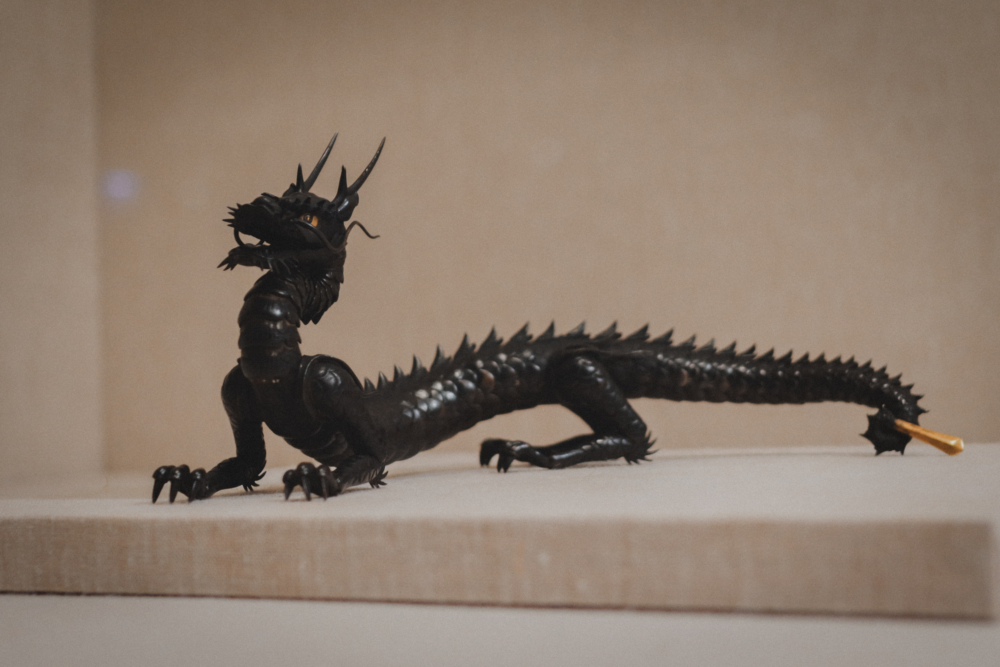 Small black bronze dragon sculpture on museum plinth — Japanese collection