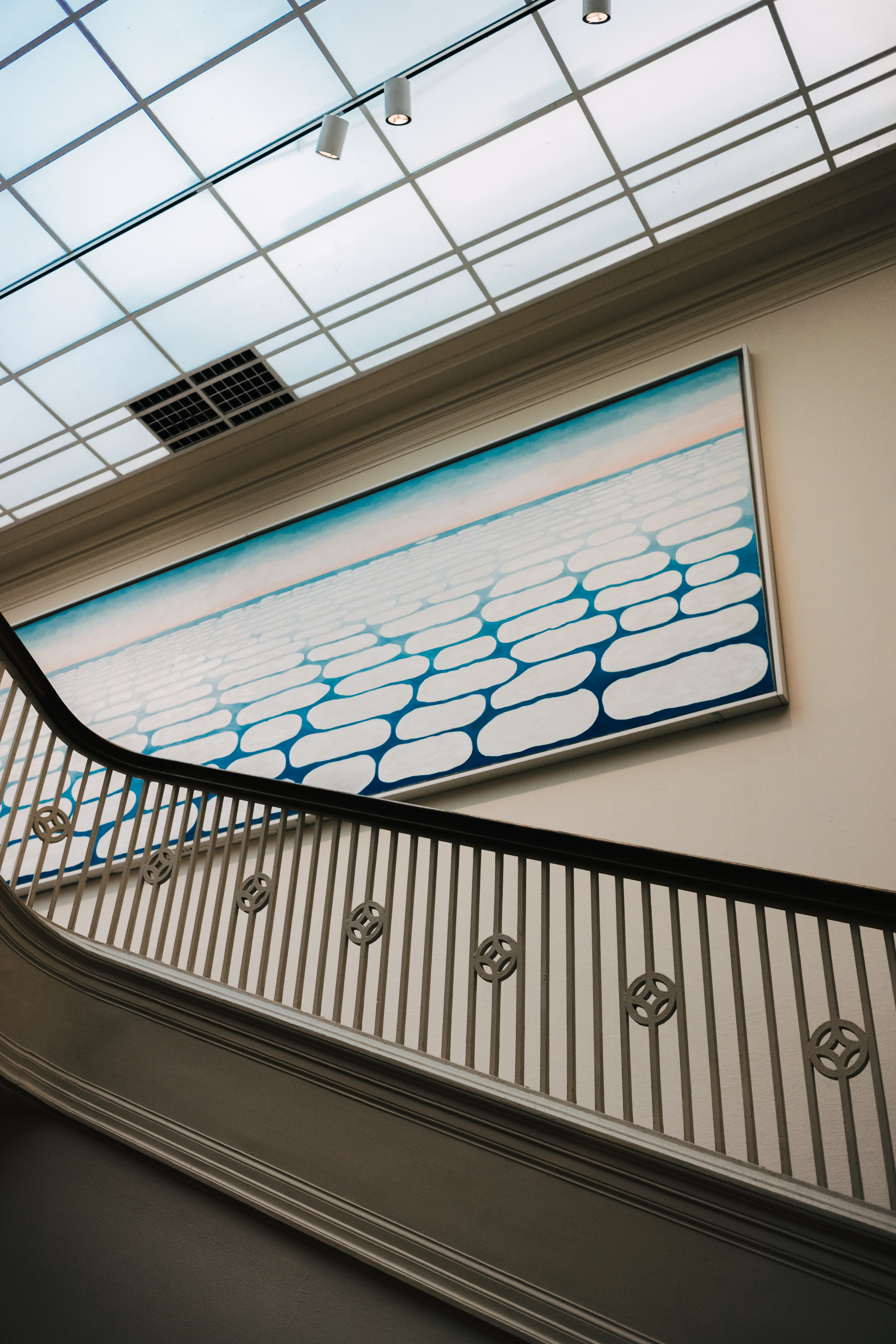 Modern Wing staircase — a massive sky-blue painting covers the wall above