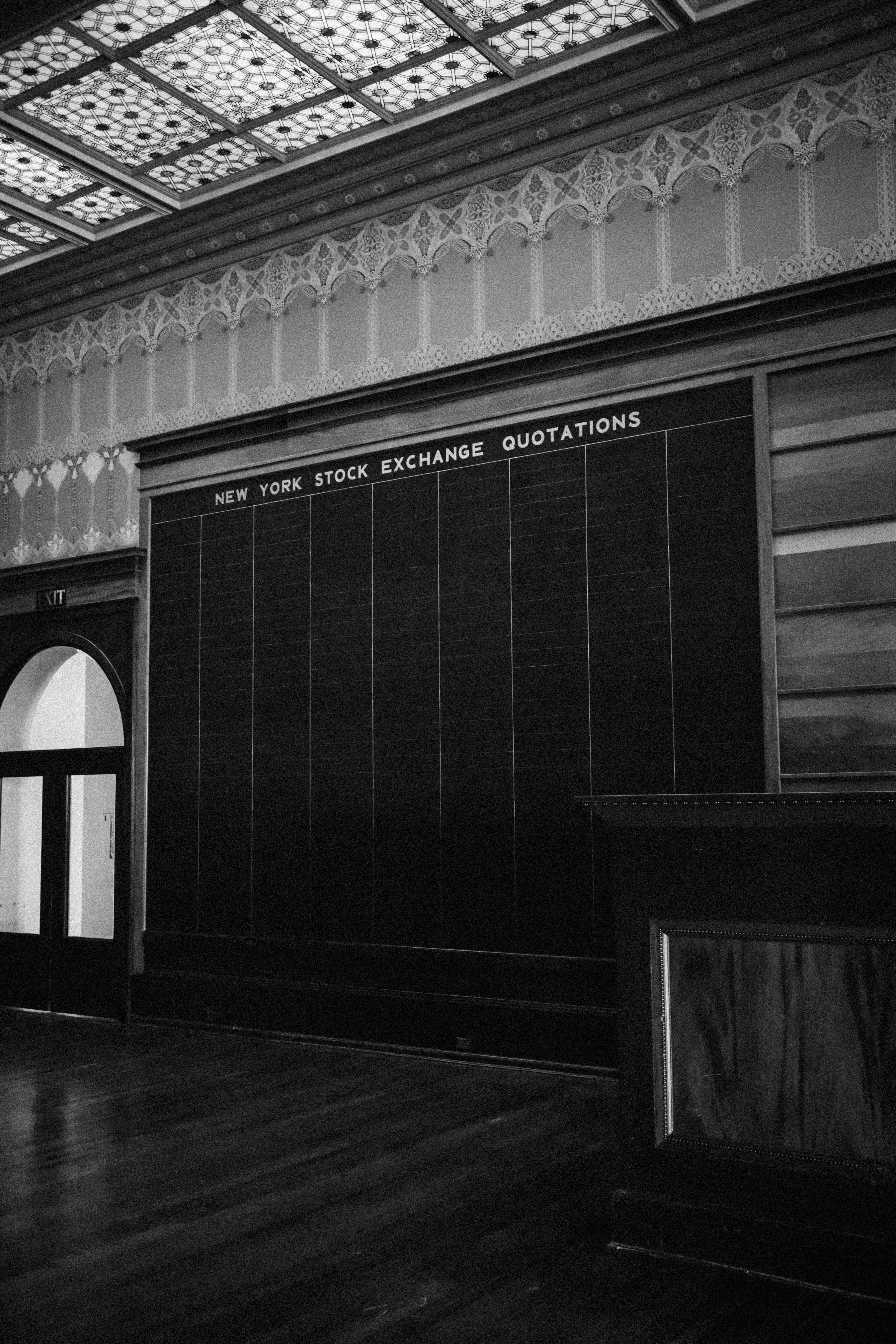 New York Stock Exchange Quotations board in black and white — ornate Sullivan ceiling above