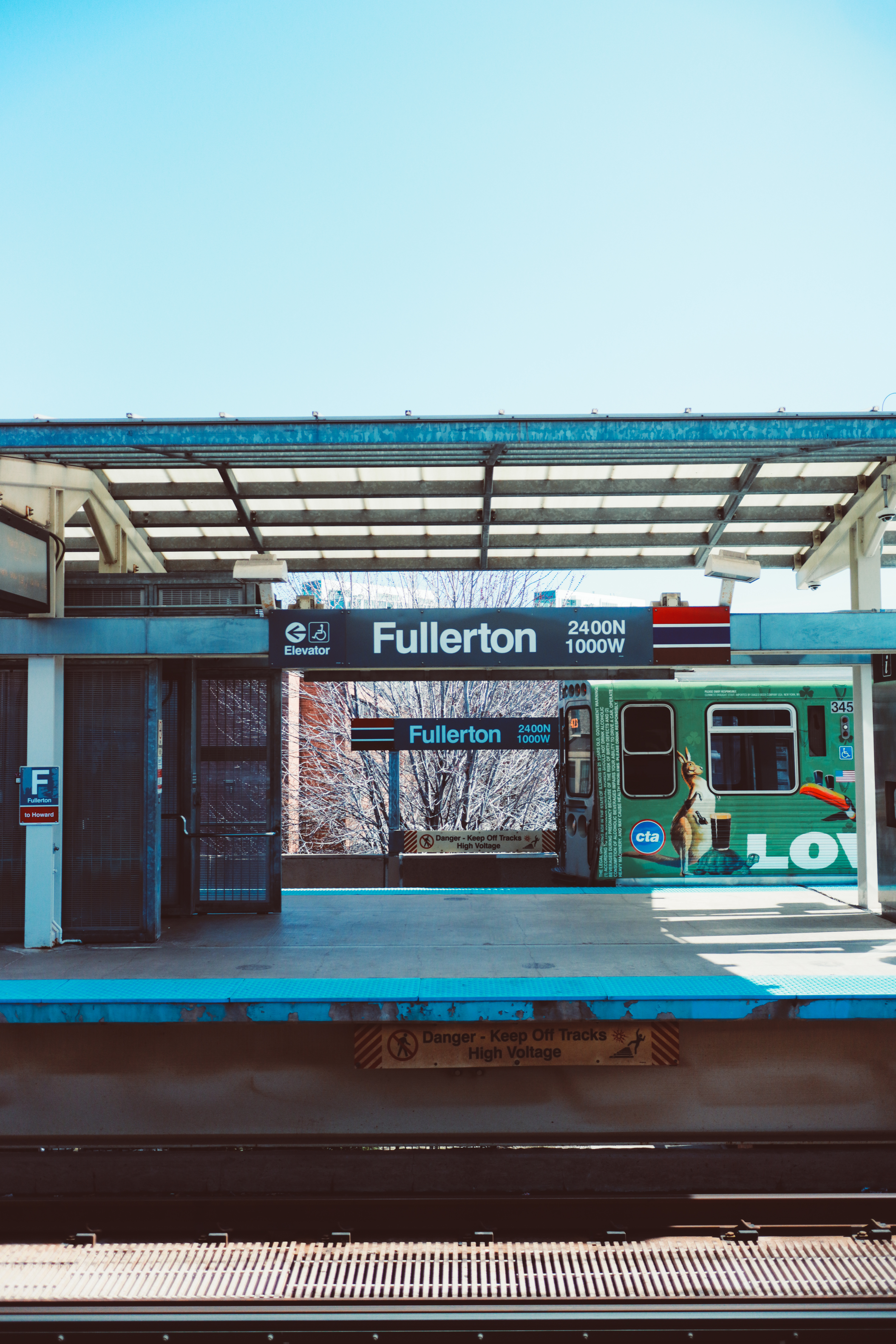 Fullerton CTA station — green line train visible through station frame, bright blue sky