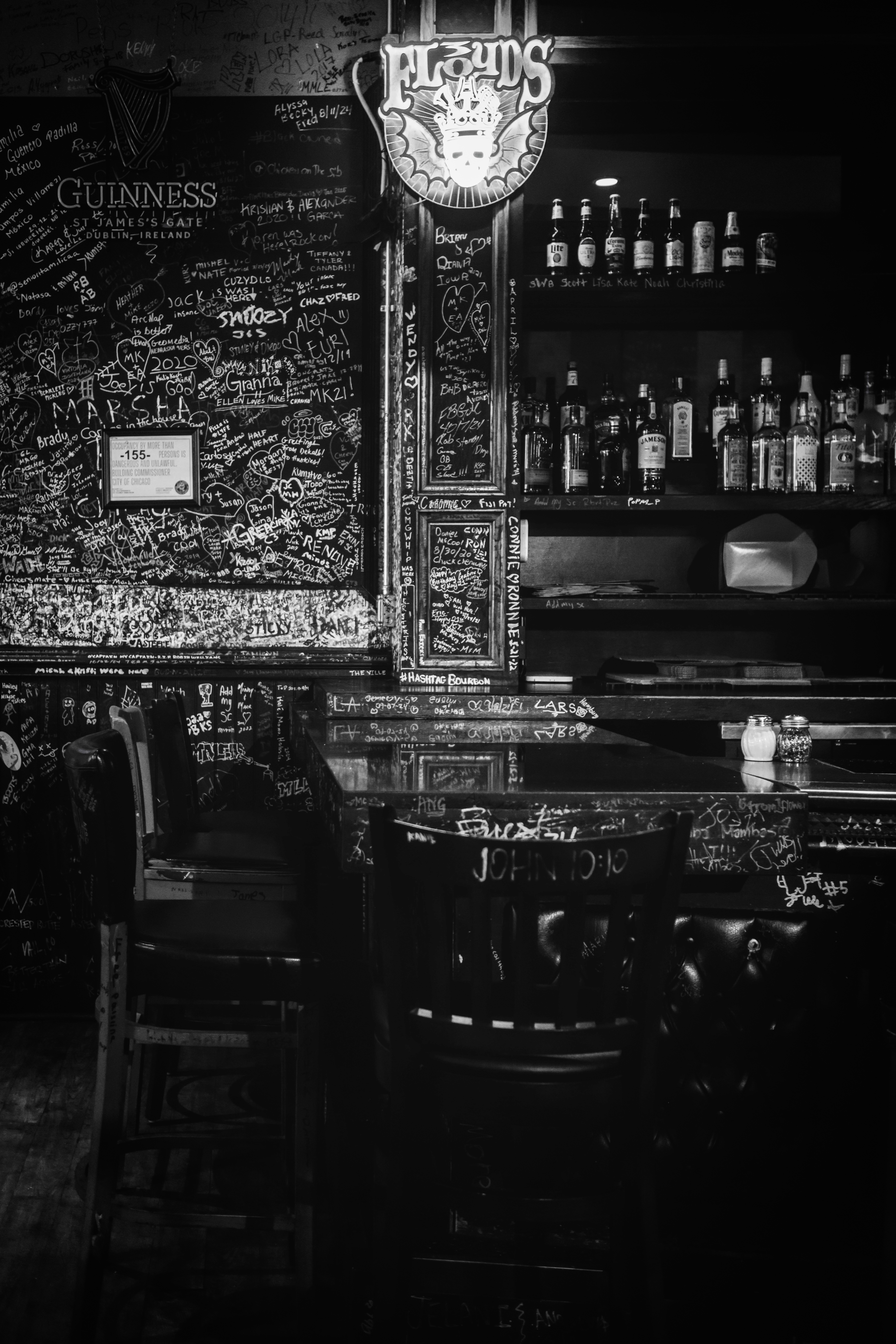 Floyd's bar interior in black and white — Guinness sign, graffiti walls, bottles behind bar