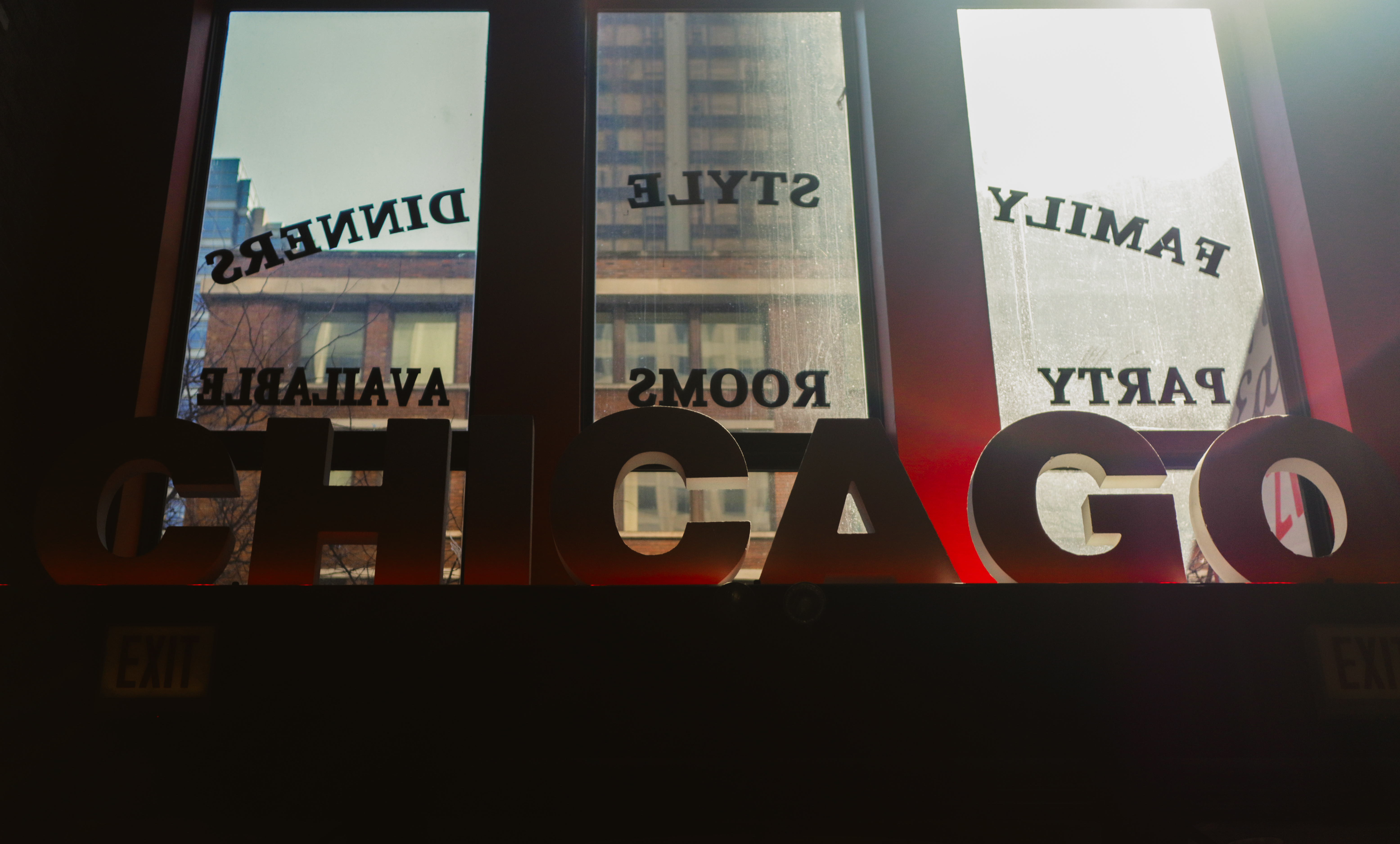 Gino's East — CHICAGO letters on window, city buildings reflected in glass behind